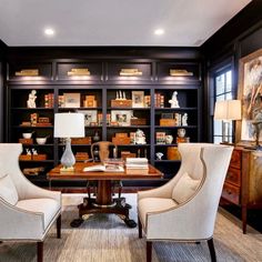 an office with two chairs and a desk in front of a bookcase filled with books