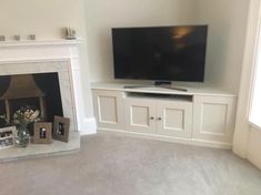 a flat screen tv sitting on top of a white mantle next to a fire place