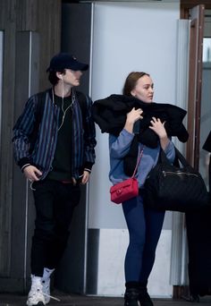 two people are walking down the street with their handbags in each other's pockets