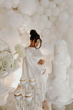 a pregnant woman standing in front of a cake