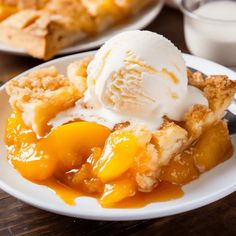 a slice of peach cobbler with ice cream on top sits on a white plate