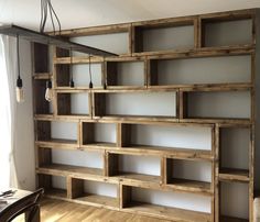 an empty room with some wooden shelves on the wall and a light fixture hanging from the ceiling