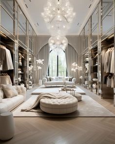 a large walk in closet filled with lots of white furniture and chandelier hanging from the ceiling