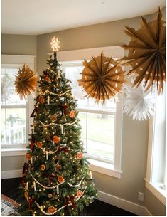 a decorated christmas tree in the corner of a room with paper stars hanging from the ceiling