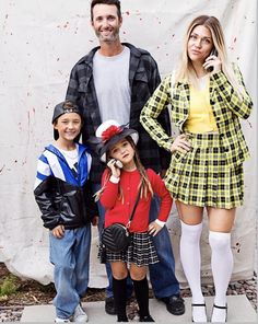 a man, woman and two children are posing for a photo in front of a white backdrop