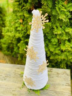 a small white christmas tree with gold snowflakes on it sitting on a wooden table