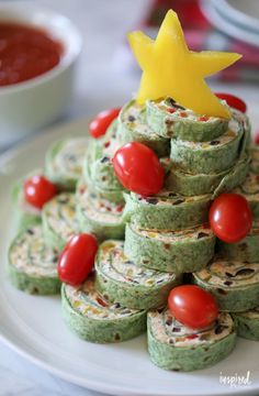 a christmas tree made out of cookies and tomatoes on a plate with sauces in the background