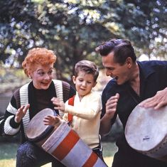 two adults and a child are playing with drums