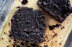 two pieces of chocolate cake sitting on top of a wooden cutting board