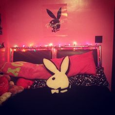 a bed with pink walls and bunny ears on the headboard is lit up by fairy lights