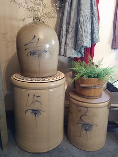 three ceramic pots with designs on them are next to a planter and coat rack