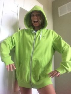 a woman in a lime green hoodie standing next to a white door with her hands on her hips