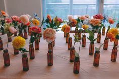 there are many small vases with flowers in them on the tableclothed table