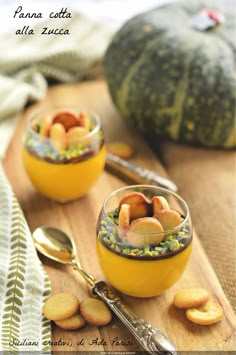 two small bowls filled with food on top of a wooden table next to pumpkins