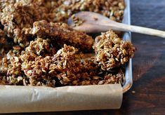 a tray filled with granola sitting on top of a table next to a wooden spoon