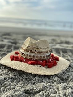 Decorated straw hat, fits size medium to small. Our Dahlia hat is a beautiful and comfortable must have for any occasion. It's decorated with red pom pom, gold and silver seashells, brown button trim and camel suede trim. Each hat is 100% made by hand and made by daily inspirations. No two hats are the same. Festival Fedora With Short Brim In Natural Color, Natural Fedora With Short Brim For Festivals, Natural Short Brim Fedora For Festival, Bohemian Straw Hat For Kentucky Derby, Red Straw Hat For Spring, White Bohemian Straw Fedora, Bohemian White Straw Fedora, Bohemian Natural Panama Hat For Kentucky Derby, Kentucky Derby Bohemian Straw Hat With Curved Brim