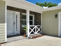 the front porch of a house with two doors and a planter on the side