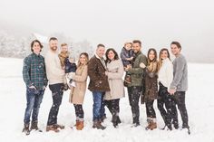 a large group of people standing in the snow with one woman holding a baby and two men looking at the camera