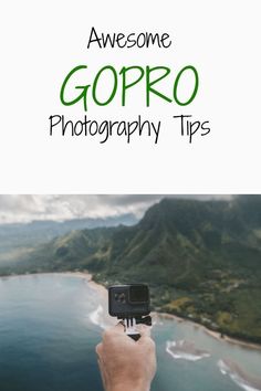 someone taking a photo with their camera on top of a hill overlooking the ocean and mountains