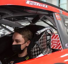 a man wearing a face mask sitting in a race car