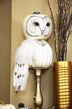 an owl statue sitting on top of a table next to a vase with branches in it