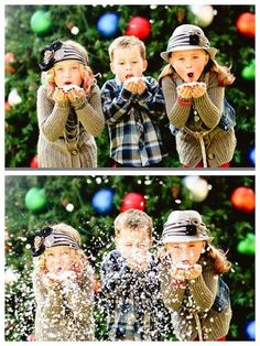 two children are playing in front of a christmas tree and one boy is blowing snow