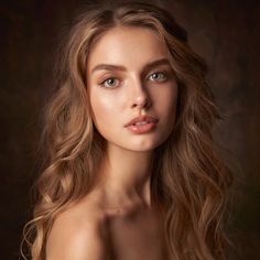 a beautiful young woman with long blonde hair posing for a photo in front of a dark background