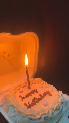 a birthday cake sitting on top of a white plate with a lit candle in it