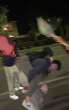 three men are skateboarding down the street at night