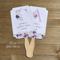 two fans with flowers on them sitting on top of a wooden table