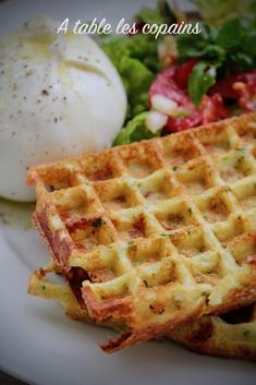 two waffles sitting on top of a white plate next to a salad and an egg