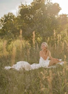 a beautiful blonde woman sitting in the middle of a field with her legs crossed and looking at the camera