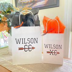 two bags sitting on top of a table next to a vase with flowers in it