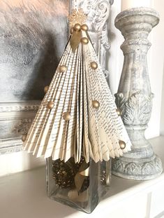 a christmas tree made out of old book pages in a vase on a mantel