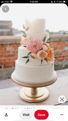 a three tiered white cake with pink and orange flowers on the top is sitting on a gold pedestal