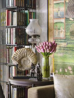 a living room filled with furniture and bookshelves next to a vase full of flowers