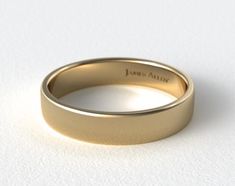 a yellow gold wedding ring on a white surface