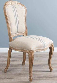 an old chair is upholstered with fabric on the seat and back, in front of a blue wall