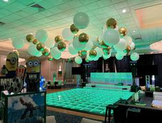 a room filled with lots of green and white balloons