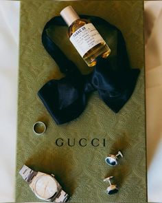 a bottle of gucci sitting on top of a table next to cufflinks