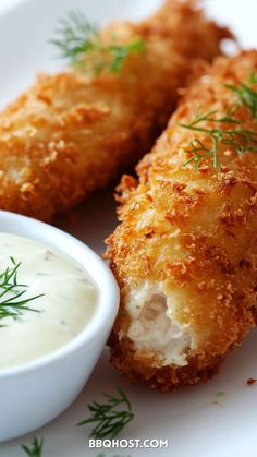 some fried food on a white plate with a small bowl of ranch dressing next to it