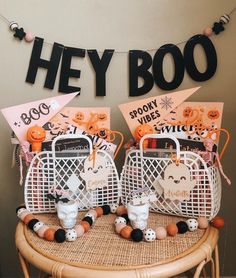 two baskets filled with halloween items on top of a table next to a sign that says hey boo