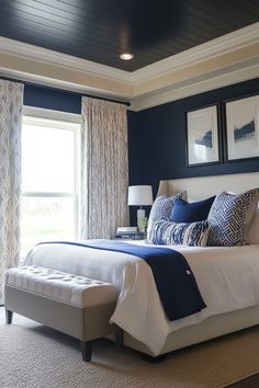 a bedroom with blue and white bedding, two framed pictures on the wall above it