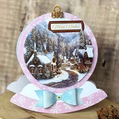 a christmas card on top of a piece of wood next to a pile of pine cones