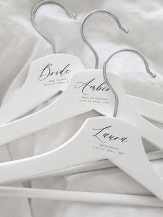 three white wooden hangers with names on them