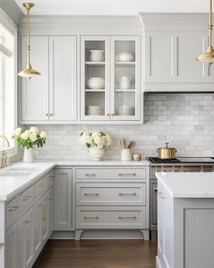 a kitchen with white cabinets and gold hardware on the doors, counter tops and drawers