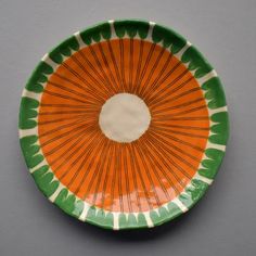 an orange and green plate on a gray surface with white circle in the center,