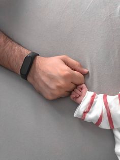 a man holding the hand of a baby