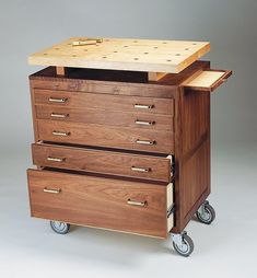 a wooden cart with three drawers on it's wheels and one drawer is open