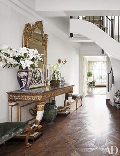 an elegant entry way with white flowers on the table and stairs leading up to the second floor